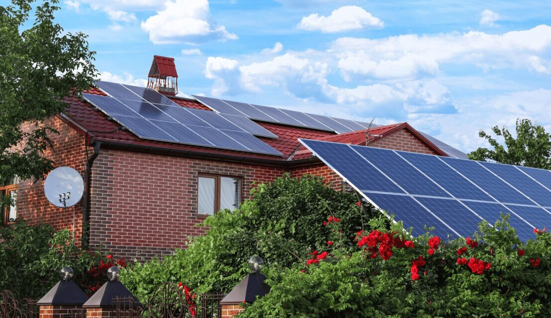 Solar panels installed on a residential roof beside a garden